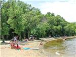 People lakeside surrounded by large trees at LAKELAND CAMPING RESORT - thumbnail