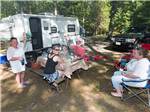 A group of people sitting around a travel trailer at CIRCLE CG FARM CAMPGROUND - thumbnail