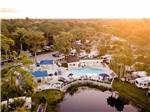 Aerial view of a resort with pond, pool and RVs amid tall trees at BLUEWAY RV VILLAGE - thumbnail