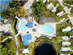 Aerial view of pool near RVs parked in lush sites at BLUEWAY RV VILLAGE - thumbnail
