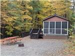 A rental cabin with a bench and fire pit at JELLYSTONE PARK ™ AT BIRCHWOOD ACRES - thumbnail