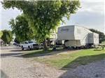 A fifth wheel trailer parked under a tree at MORRILTON I40/107 RV PARK - thumbnail