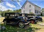 A row of classic cars next to the white building at MEADOWBROOK CAMPING AREA - thumbnail