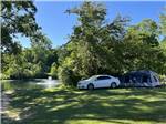 A car and a tent in grass by the water at LANSING COTTONWOOD CAMPGROUND - thumbnail
