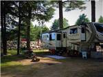 A fifth wheel travel trailer parked under trees at LAKE GEORGE RIVERVIEW CAMPGROUND - thumbnail