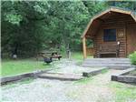 Cabin with picnic table and gravel parking space at FORT SMITH-ALMA RV PARK - thumbnail
