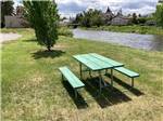 A picnic table by the river at DEER LODGE A-OK CAMPGROUND - thumbnail