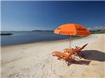 An orange umbrella and two lounge chairs at the beach at SUN OUTDOORS CAPE CHARLES - thumbnail