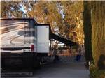 Large brown, tan and white travel trailer with awning at SANTA NELLA RV PARK - thumbnail