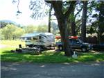 A trailer and truck under a tree at CASINI RANCH FAMILY CAMPGROUND - thumbnail