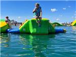 A kid jumping off an inflatable slide on the lake at STONEY CREEK RV RESORT - thumbnail