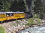 A yellow train going by the river nearby at ALPEN ROSE RV PARK - thumbnail