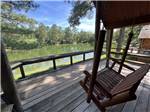 A deck with a swing overlooking the water at TALLAHASSEE EAST CAMPGROUND - thumbnail