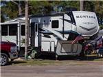 A Montana fifth wheel with flags in a paved site at CAMPER'S INN - thumbnail