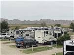 RVs parked on-site with mountains in the distance at BADLANDS MOTEL & CAMPGROUND - thumbnail