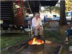 A man sitting by a fire pit at NETARTS BAY GARDEN RV RESORT - thumbnail