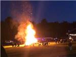 People surrounding a large bonfire at COUNTRY ROADS CAMPGROUND - thumbnail