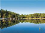 Glassy blue lake with RVs and trailers reflecting on its surface at ALPINE LAKE RV RESORT - thumbnail