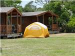 A tent in front of a row of rental cabins at FRISCO WOODS CAMPGROUND - thumbnail