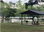 A barbecue pit and bench under a pavilion at TREASURE ISLE RV PARK - thumbnail