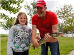 A man and girl holding a fish they caught at FISHERMAN'S COVE TENT & TRAILER PARK - thumbnail