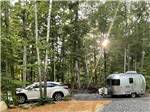 A car and trailer in an woody RV site at AUGUSTA-WEST LAKESIDE KAMPGROUND - thumbnail