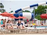 Ladies sunbathing with water slides in the background at BETHPAGE CAMP-RESORT - thumbnail