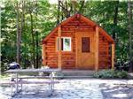 Guest cabin with picnic bench at CAMPERS COVE CAMPGROUND - thumbnail