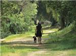 Woman walking a dog on wooded trail at RANCHO LOS COCHES RV PARK - thumbnail