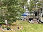A grassy area next to a fifth wheel trailer at BEECH HILL CAMPGROUND & CABINS - thumbnail