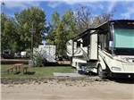 Campsite with picnic table and motorhome at GLOWING EMBERS RV PARK & TRAVEL CENTRE - thumbnail