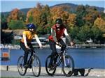 Couple riding bicycles near the water at KING PHILLIPS CAMPGROUND - thumbnail