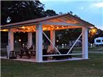 Inviting patio area with lounge chairs and decorative lighting overhead at CAJUN RV PARK - thumbnail