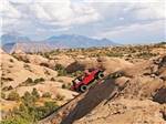 Red 4x4 jeep climbing up steep incline in the desert at SHADY ACRES RV PARK - thumbnail