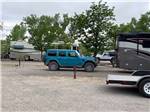 A teal Jeep parked in back of a motorhome in a RV site at SHADY ACRES RV PARK - thumbnail