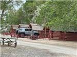 A silver car parked in front of the wooden cabins at SHADY ACRES RV PARK - thumbnail