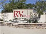 Campground front entrance sign with red font on desert themed brick wall at DESERT WILLOW RV RESORT - thumbnail