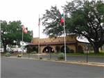 The front of the office building with three flags at FIG TREE RV RESORT - thumbnail