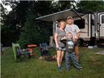 A family standing outside of their trailer at CHERRY HILL PARK - thumbnail