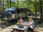 A family eating outside of their trailer at INDIAN ROCK RV PARK - thumbnail