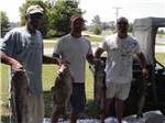 Three men holding fish at TOM SAWYER'S RV PARK - thumbnail