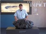 A man standing next to a rock display at the museum nearby at METEOR CRATER RV PARK - thumbnail