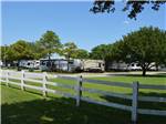 A white fence in front of RV sites at TRADERS VILLAGE RV PARK - thumbnail