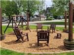 Wooden chairs and swing with a fire pit at CLARKSVILLE RV RESORT BY RJOURNEY - thumbnail