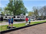 A dad and his kids playing cornhole at CLARKSVILLE RV RESORT BY RJOURNEY - thumbnail