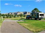 An empty RV site with a picnic table next to site with a fifth wheel hooked up to a truck at ROBIDOUX RV PARK - thumbnail