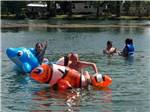 Kids playing on inflatable fish in the lake at LEHMAN'S LAKESIDE RV RESORT - thumbnail