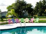 Swimming pool with colorful chairs at SONRISE PALMS RV PARK - thumbnail