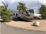 Fifth wheel parked between trees in campsite at ZUNI VILLAGE RV PARK - thumbnail