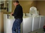 A man using one of the washing machines at VICTORIAN RV PARK - thumbnail